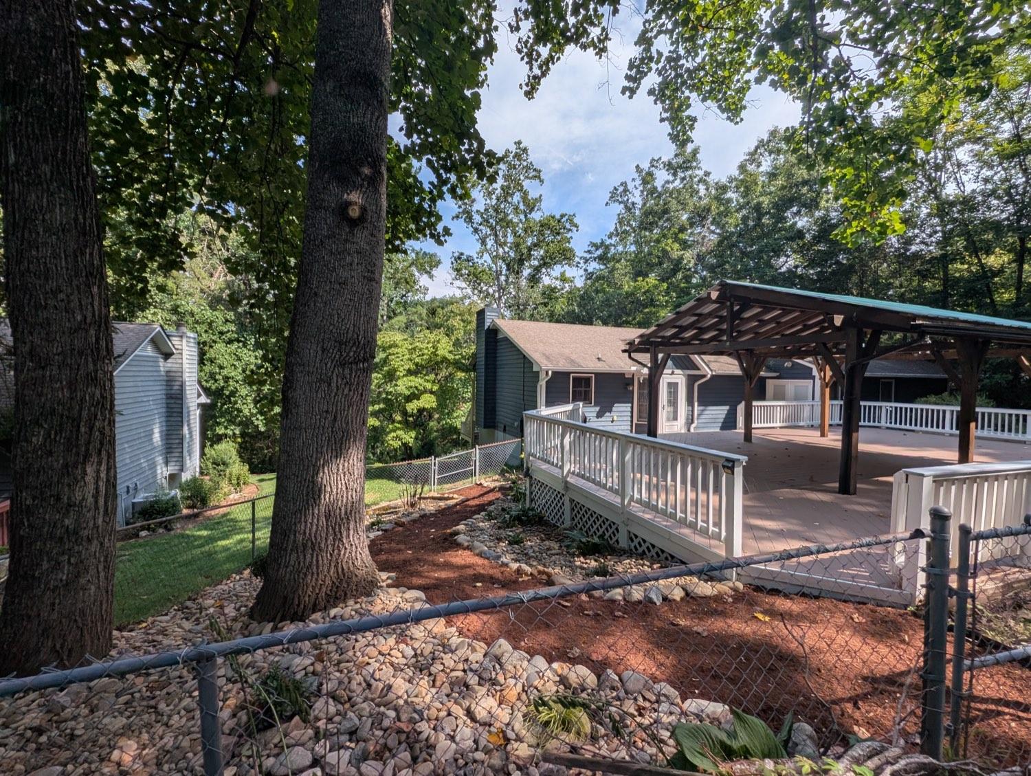 A cleared yard with mulched beds, a river-rock border and a gravel path beside the deck.